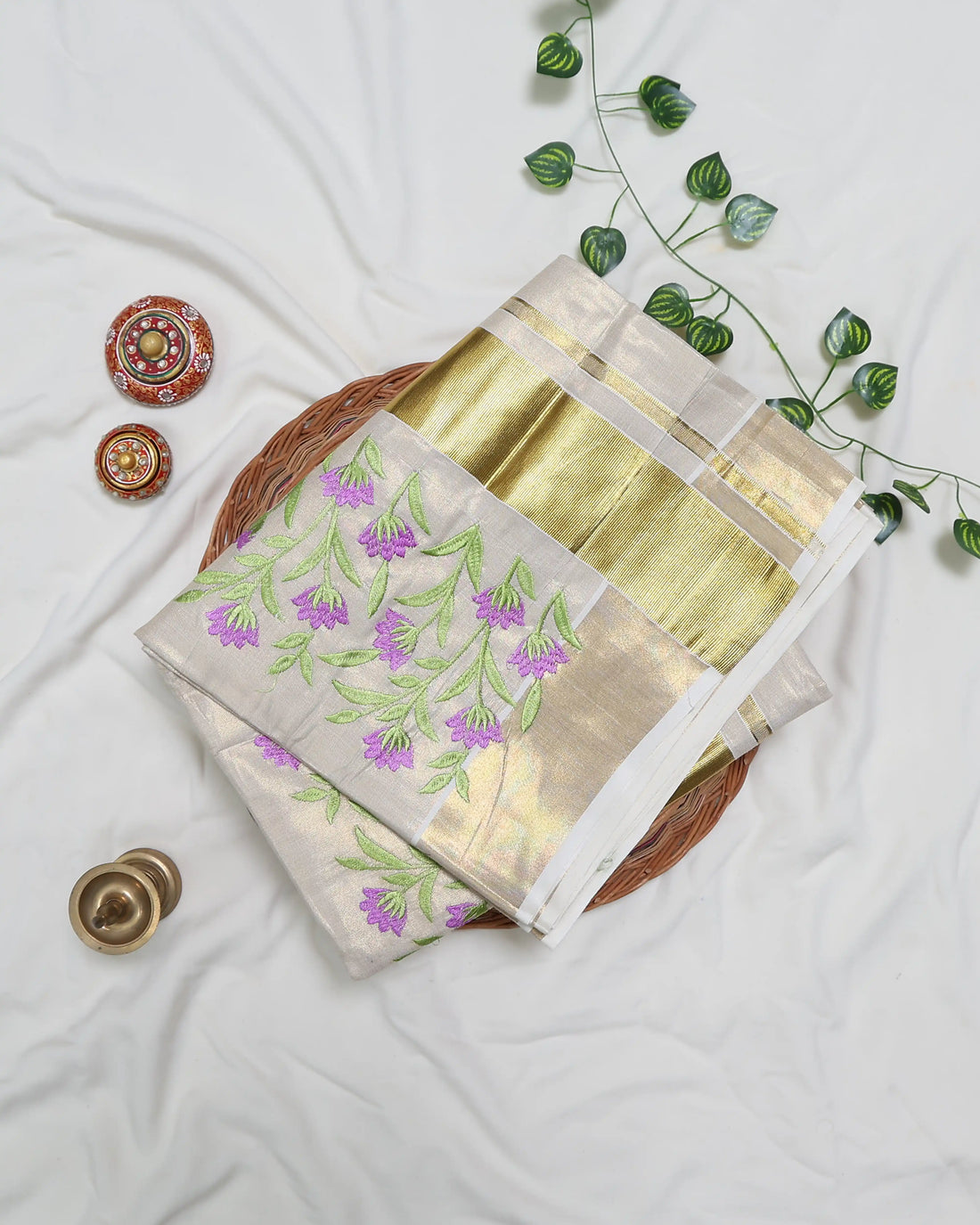A cream-colored Kerala saree with purple and green floral embroidery full view