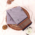 Kanchi Cotton Saree With Zari Border In Lavender Neatly Folded On Wicker Basket Top View Display
