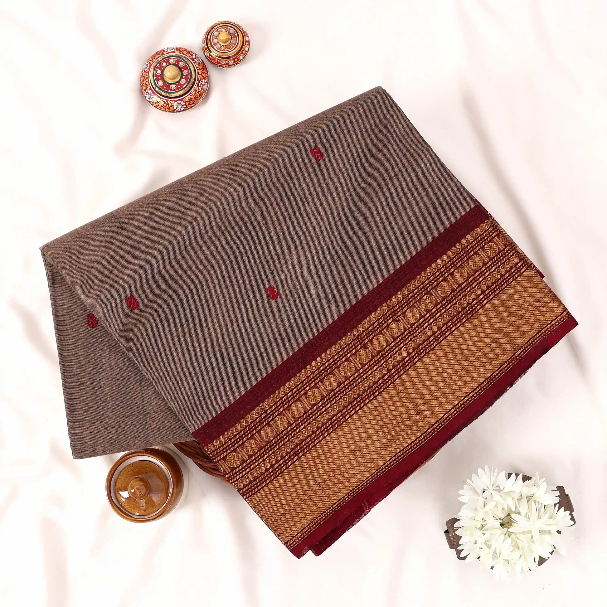 Chettinad cotton saree with zari buttas and zari border in Light brown and maroon folded top view
