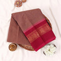 Chettinad cotton saree in brown with a contrast magenta zari woven peacock border folded flat lay front view.