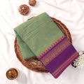 Kanchi Cotton Saree With Zari Woven Purple Border And Pastel Green Body Folded Flat Lay View With Decorative Accents
