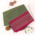 Chettinad cotton saree with green plain body temple zari border and woven butta motifs folded top view.