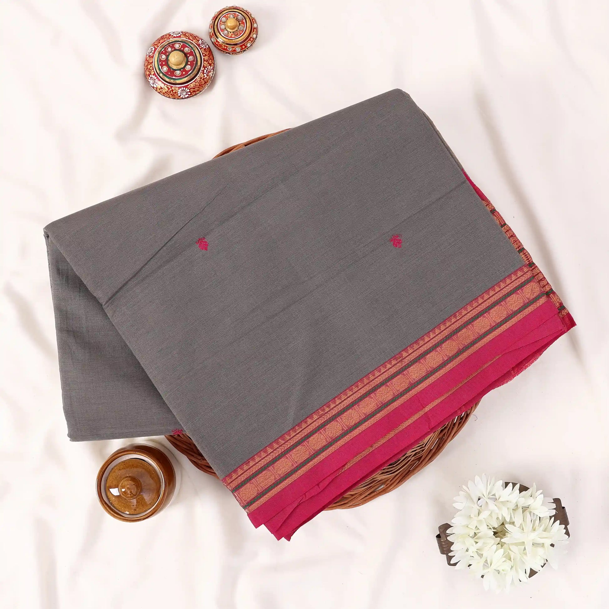 Chettinad cotton saree with light grey plain body temple zari border and woven butta motifs folded top view.