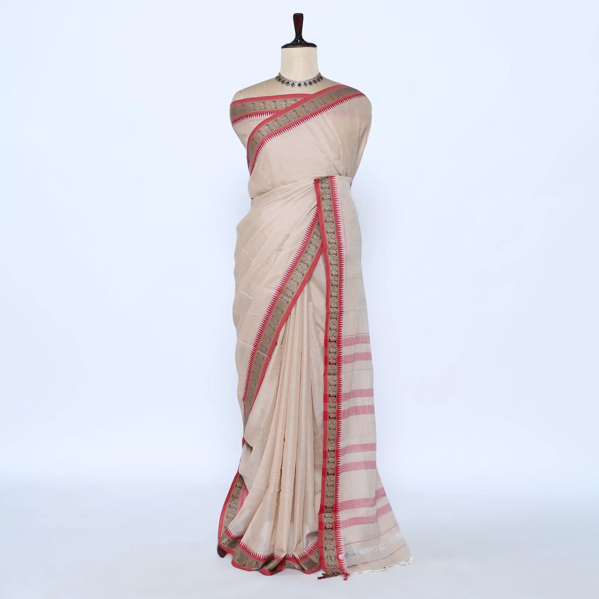A light beige cotton saree with pink stripes and a red and gold border