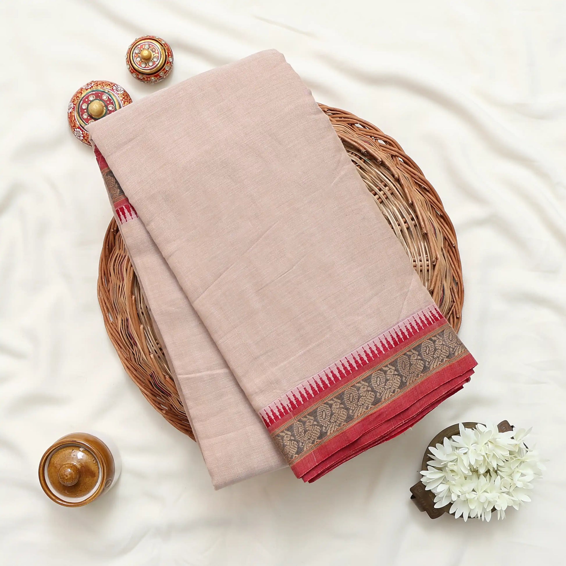 A folded light beige or dusty pink the fabric features a decorative border with red and gold patterns.