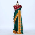 A dark green silk saree with a wide mustard yellow and gold checkered border, blouse is maroon with gold  woven borders.