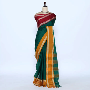 A dark green silk saree with a wide mustard yellow and gold checkered border, blouse is maroon with gold  woven borders.