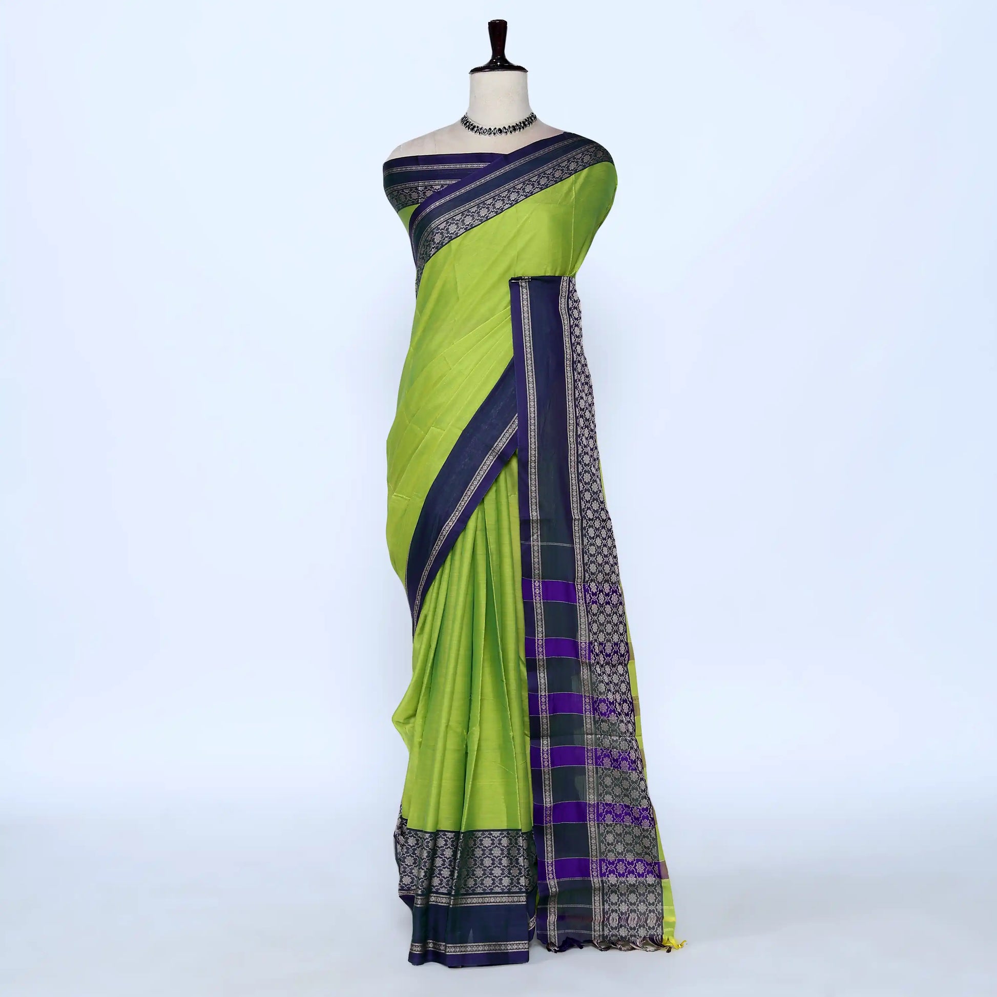 A green and navy blue saree with purple and gold patterned borders