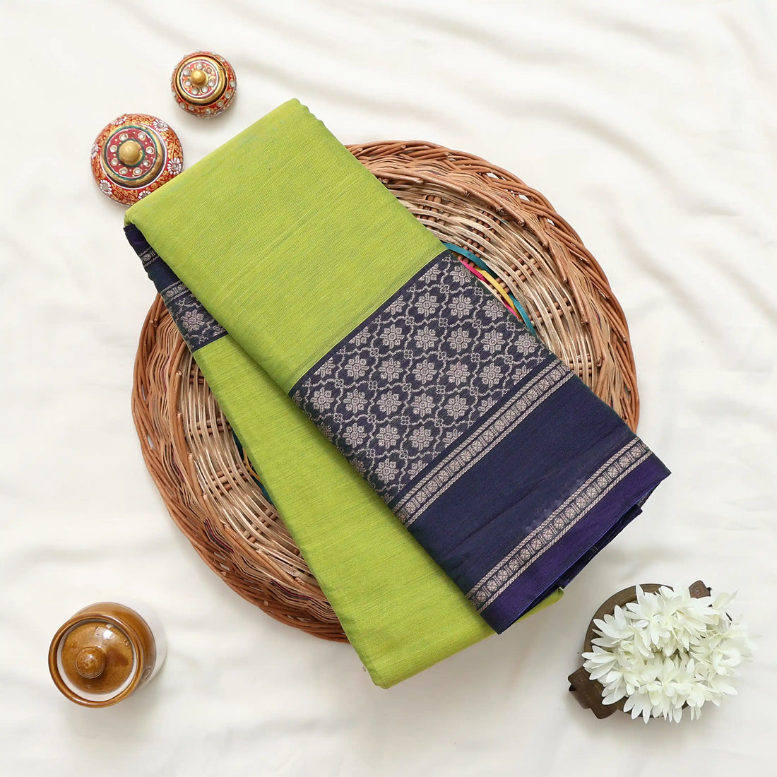 A green and navy blue saree with purple and gold patterned borders