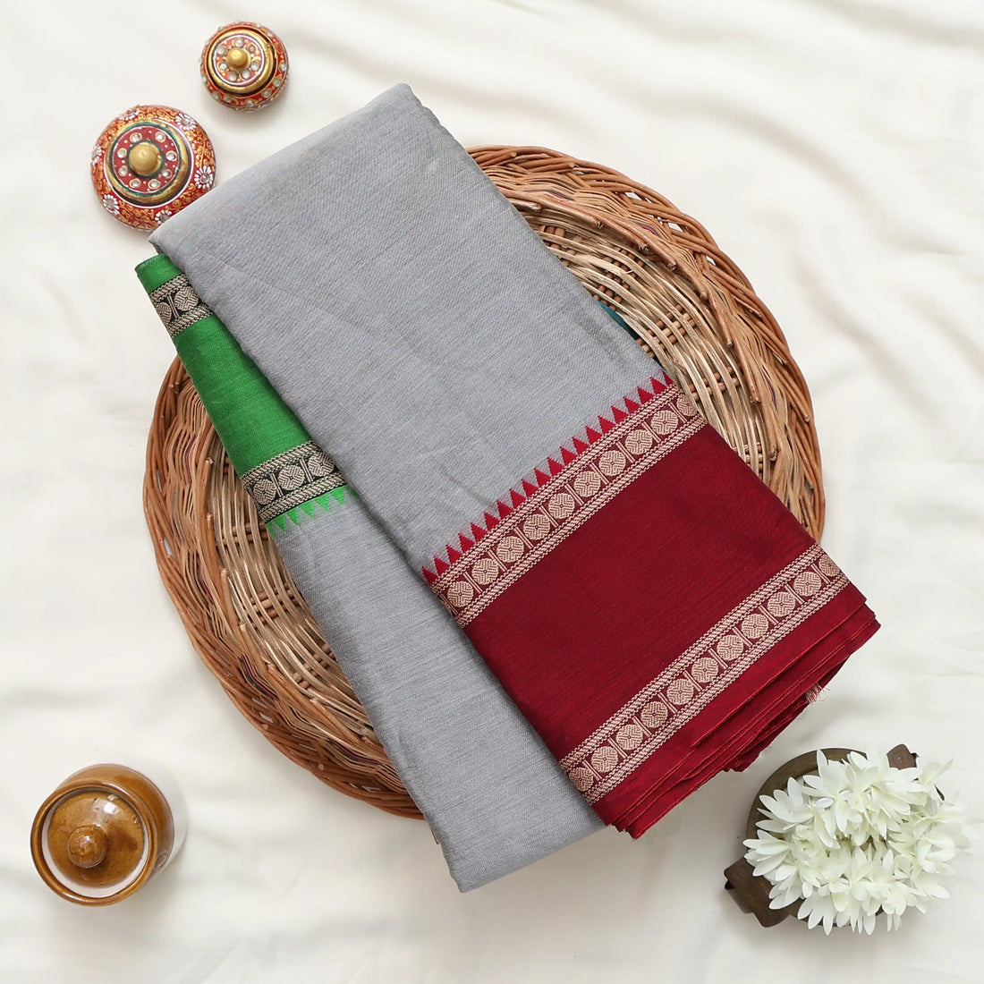 A gray and green saree with a deep red and green border