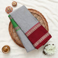 A folded gray fabric garment or textile with a green section and a deep red border featuring intricate gold and white patterns