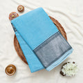 A folded light blue narayanpet saree with silver zari border 