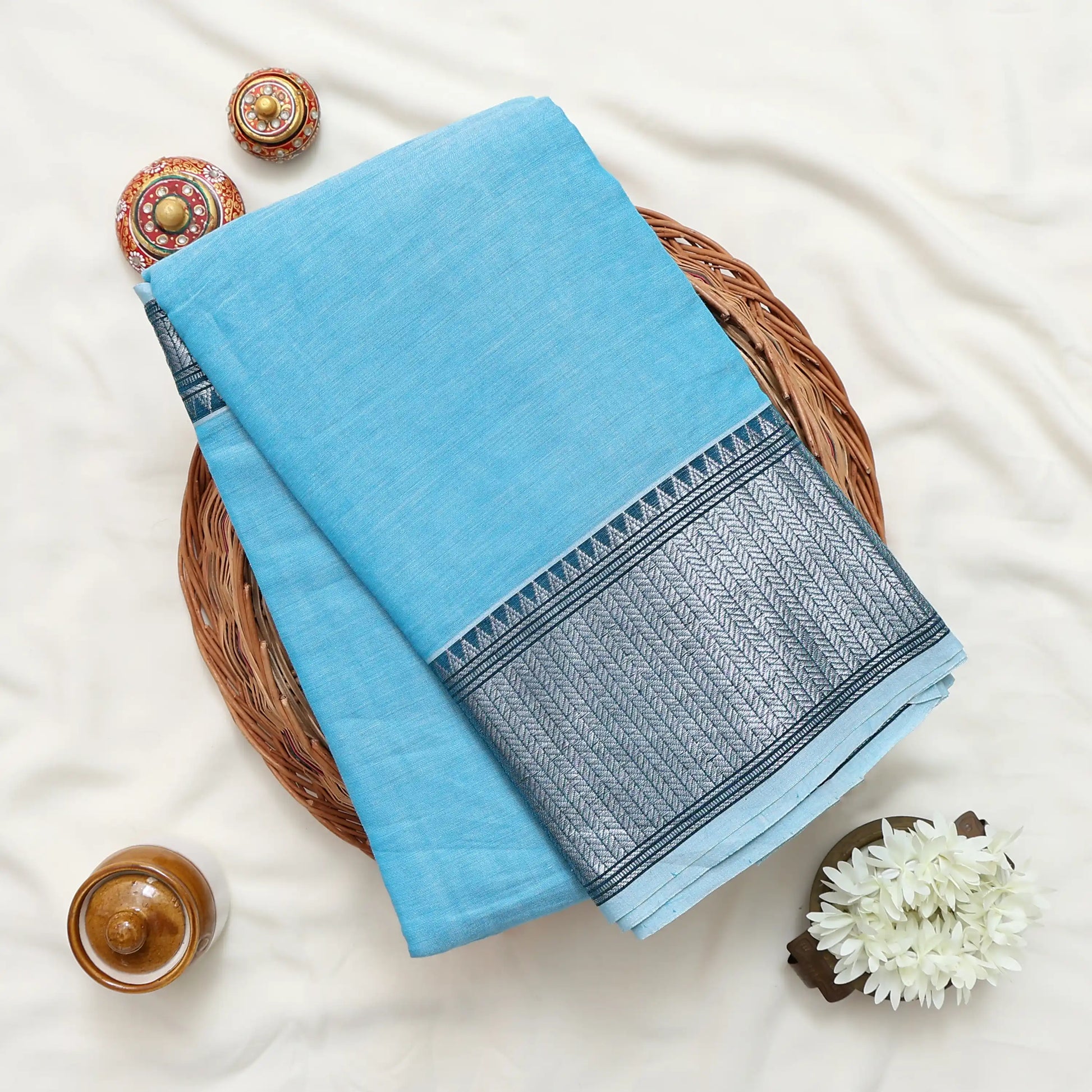 A folded light blue narayanpet saree with silver zari border 