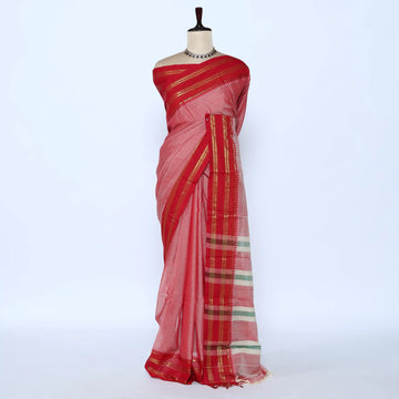 Red and pink saree with gold and green striped border folded on a woven basket display