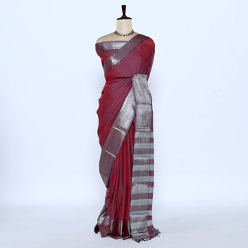 A deep red saree with a metallic silver and gold striped border