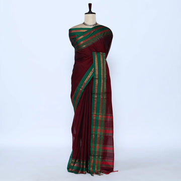 A dark red and green saree with gold and red woven stripes