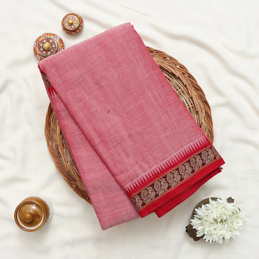 A pink cotton saree with a striped pallu and a gold patterned border