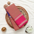 A pink and rust-colored saree with a royal blue border and gold zari stripes