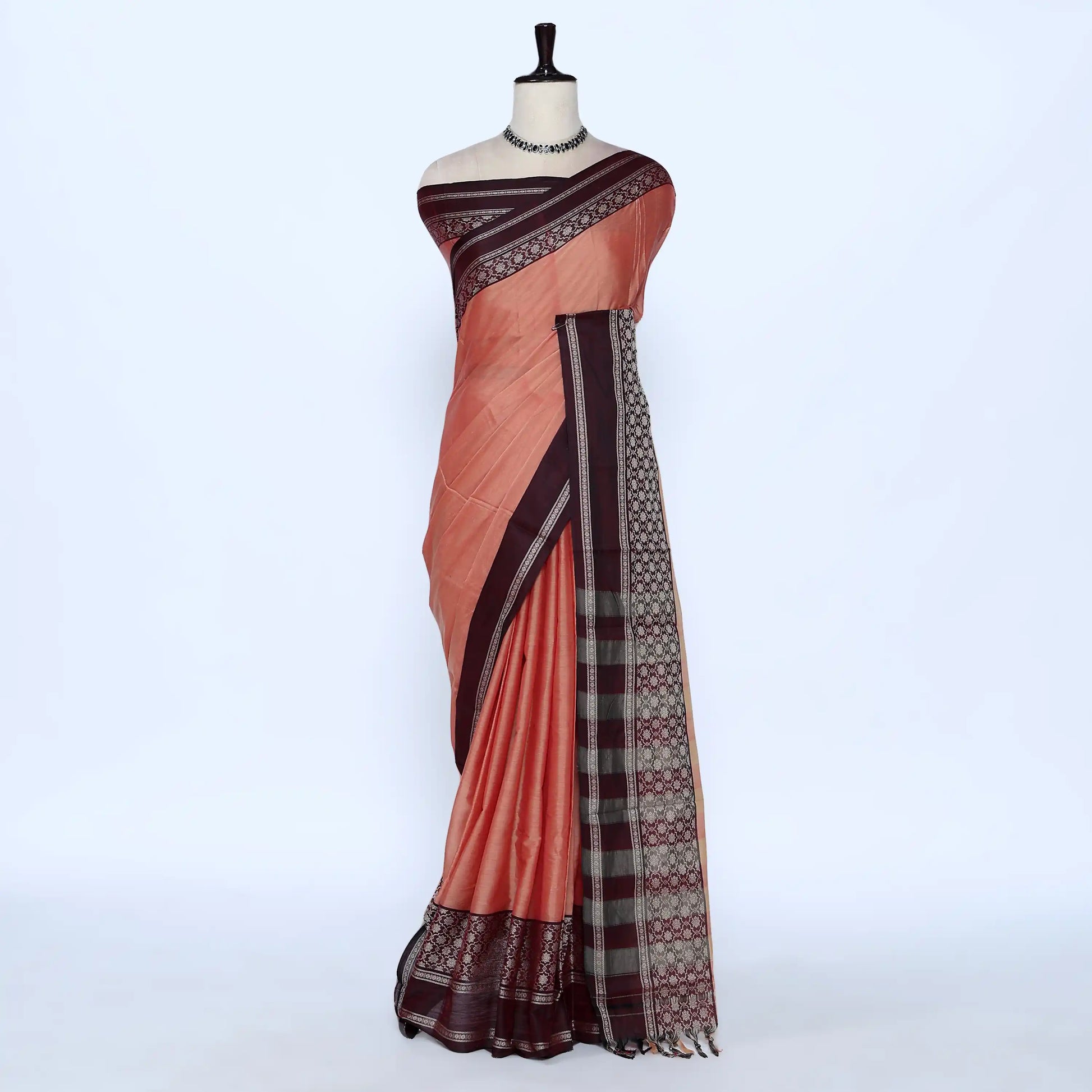 A peach-colored saree with dark brown borders and a patterned pallu