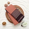 A peach-colored saree with dark brown borders and a patterned pallu