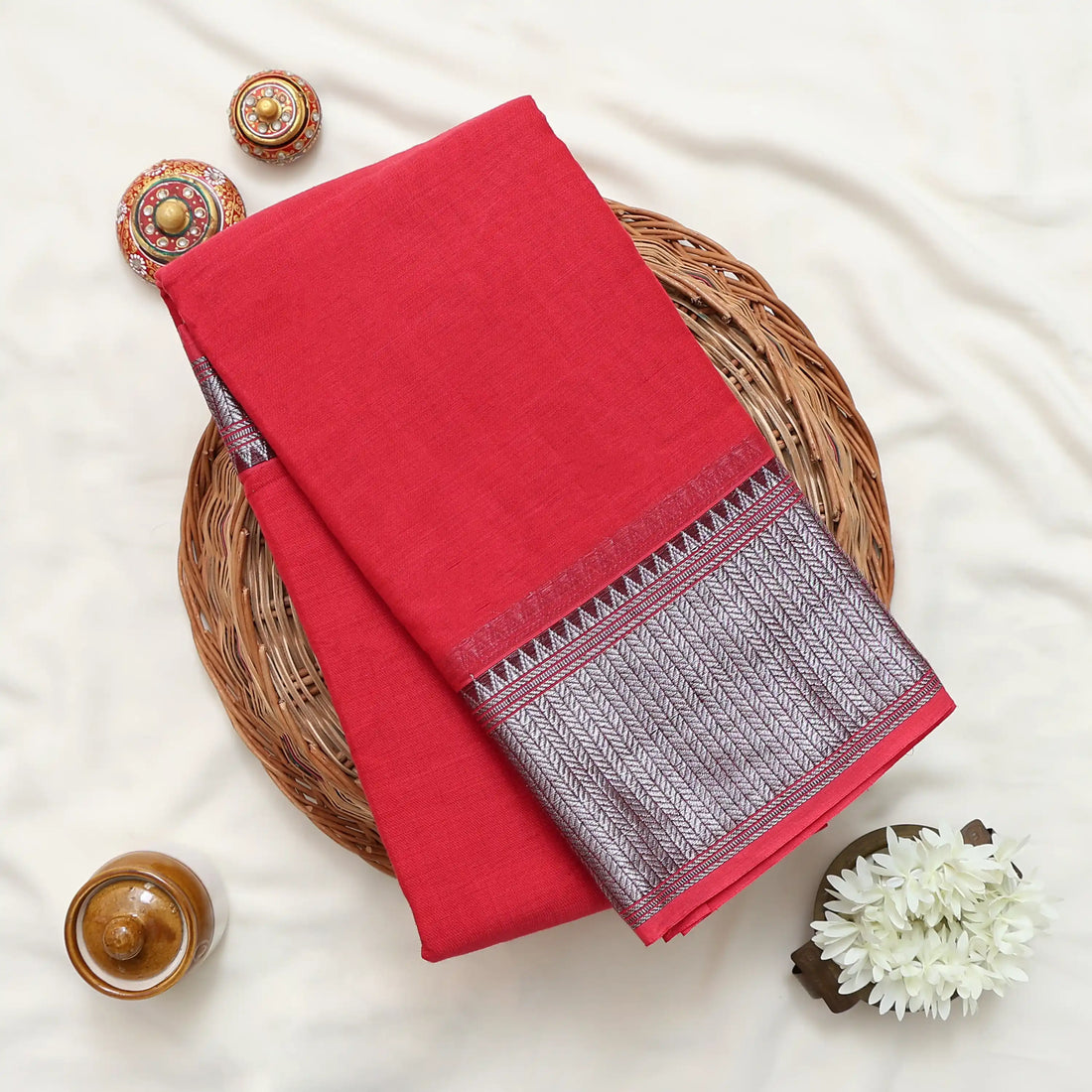 A red cotton saree with a silver metallic zari border and pallu