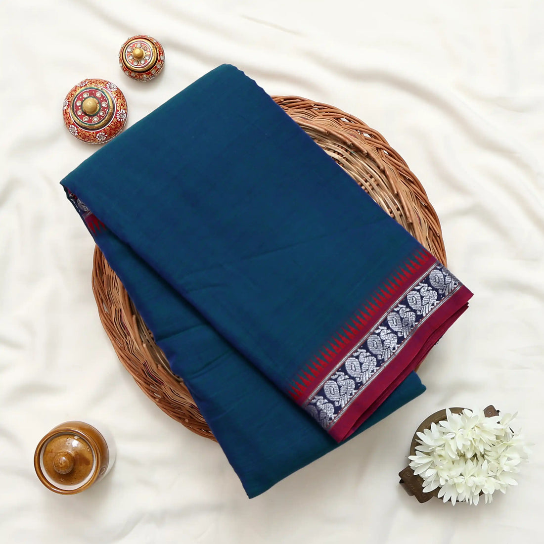 A blue and green saree with red and silver borders