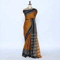 A mustard yellow and black saree featuring a black border with a white geometric pattern and a matching black-and-gold checkered pallu.
