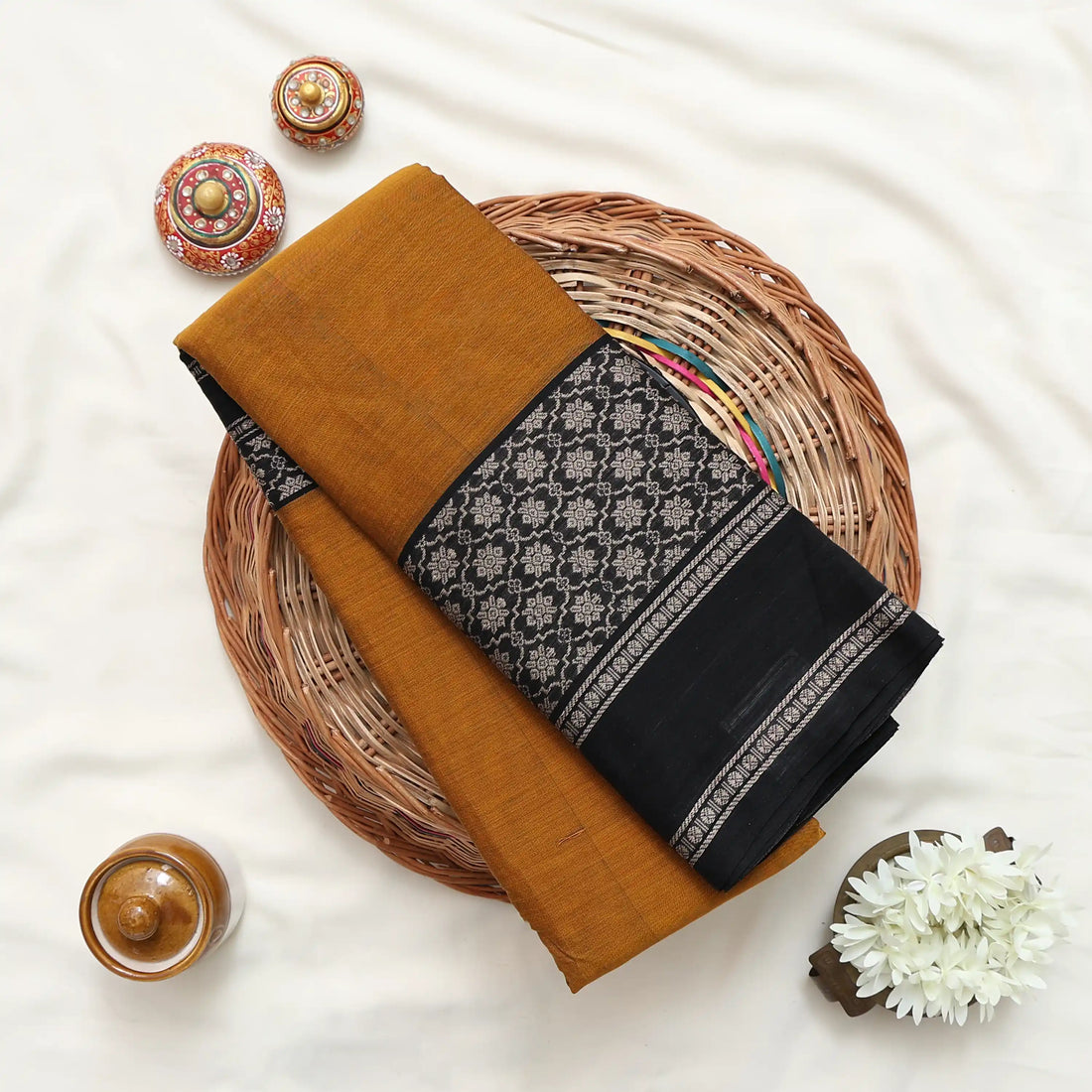 A mustard yellow and black saree featuring a black border with a white geometric pattern and a matching black-and-gold checkered pallu.