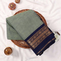 Kanchi Cotton Saree With Solid Olive Green Body And Navy Blue Zari Border Neatly Folded In Basket Top View
