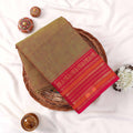 Kanchi Cotton Saree With Olive Green Body And Bright Pink Zari Border Folded Flat Lay View With Decorative Accents
