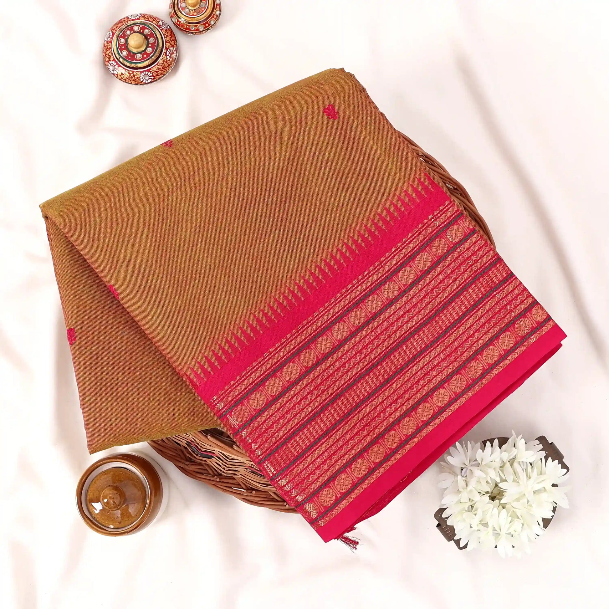 Chettinad cotton saree with plain body temple zari border and woven butta motifs folded top view.