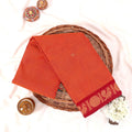 Kanchi Cotton Saree With Peacock Motif Border In Orange Color Folded Flat Lay View With Decorative Accents
