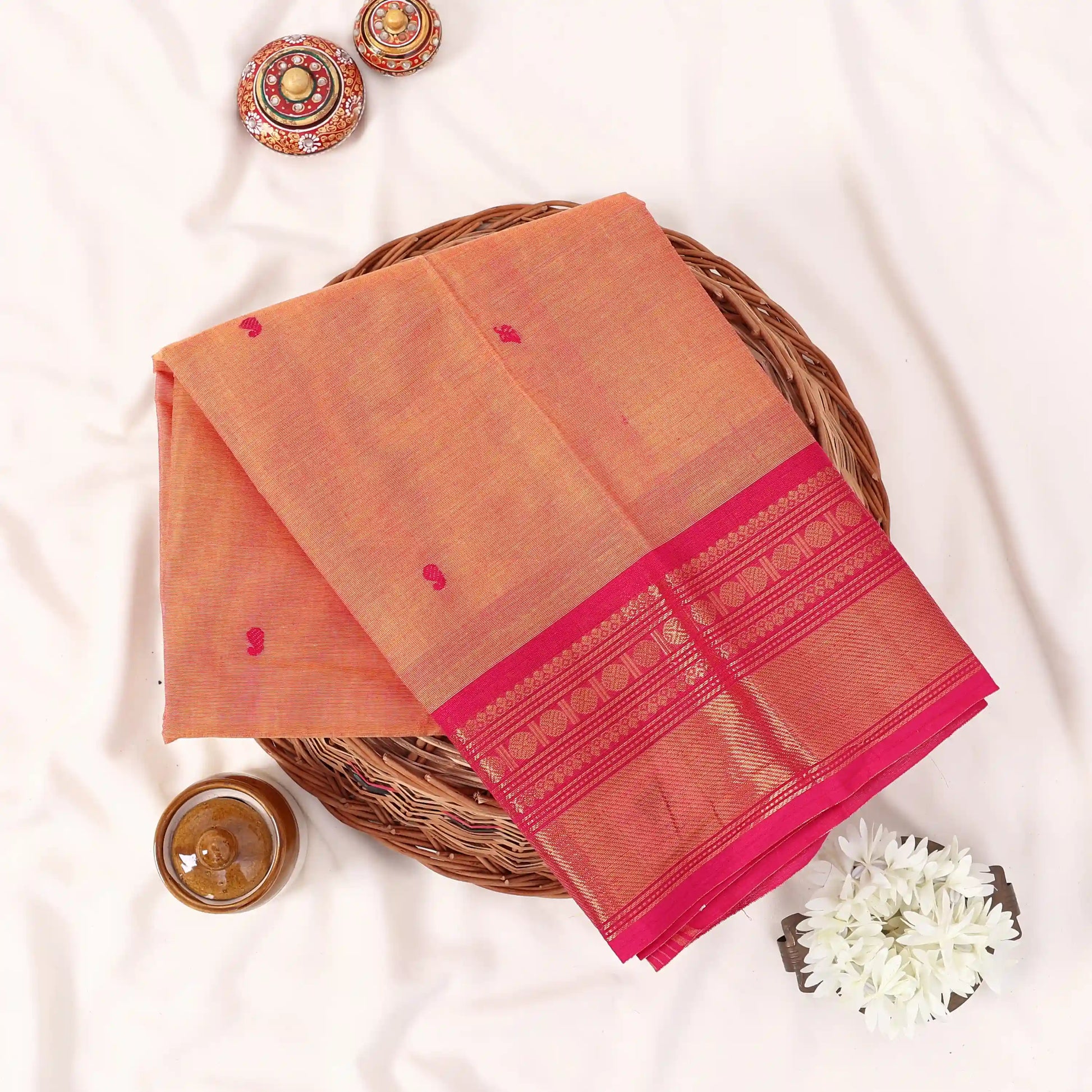 Chettinad cotton saree with zari buttas and zari border in orange and pink folded top view