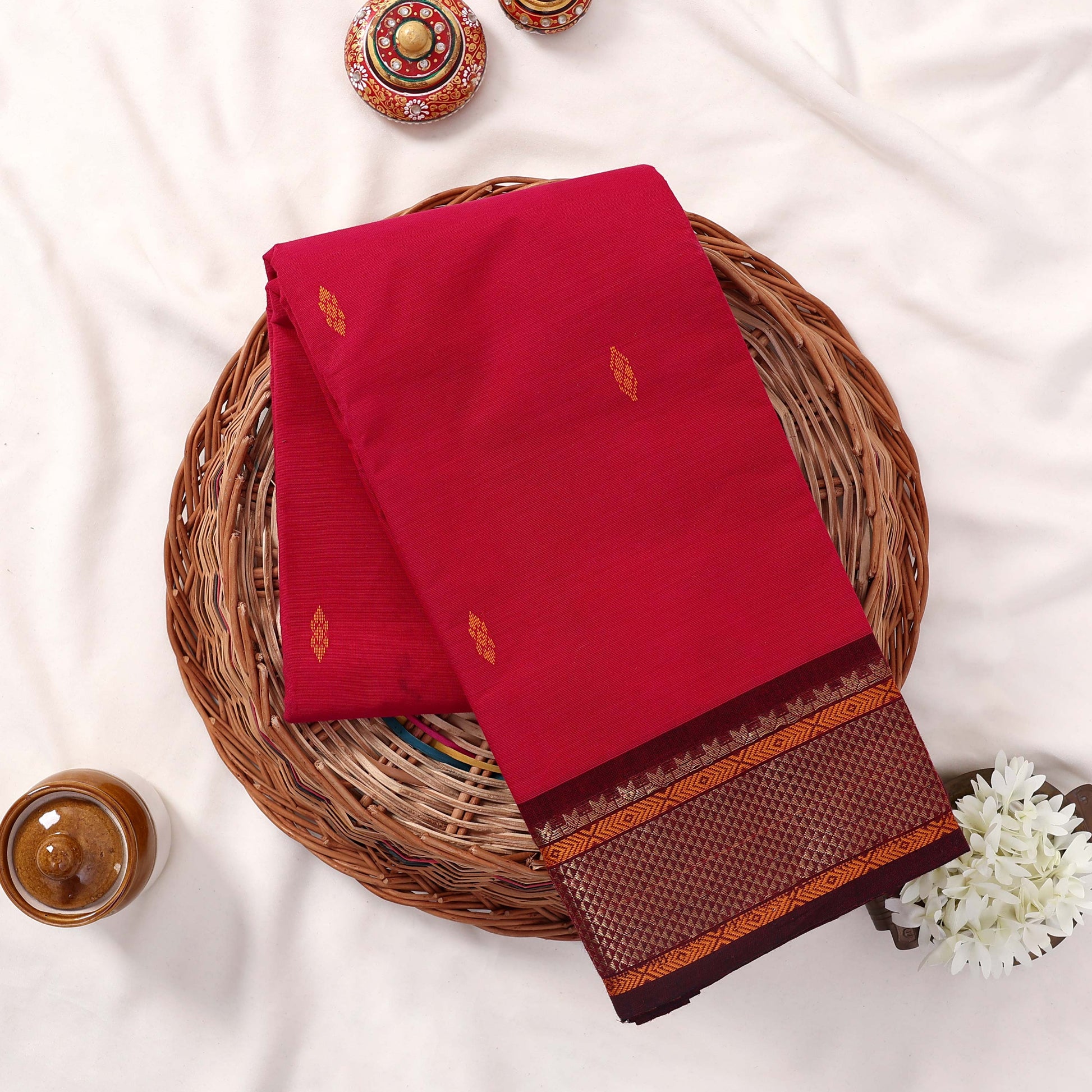 Kanchi Cotton Saree With Zari Border In Bright Pink Neatly Folded On Wicker Basket Top View Product Display
