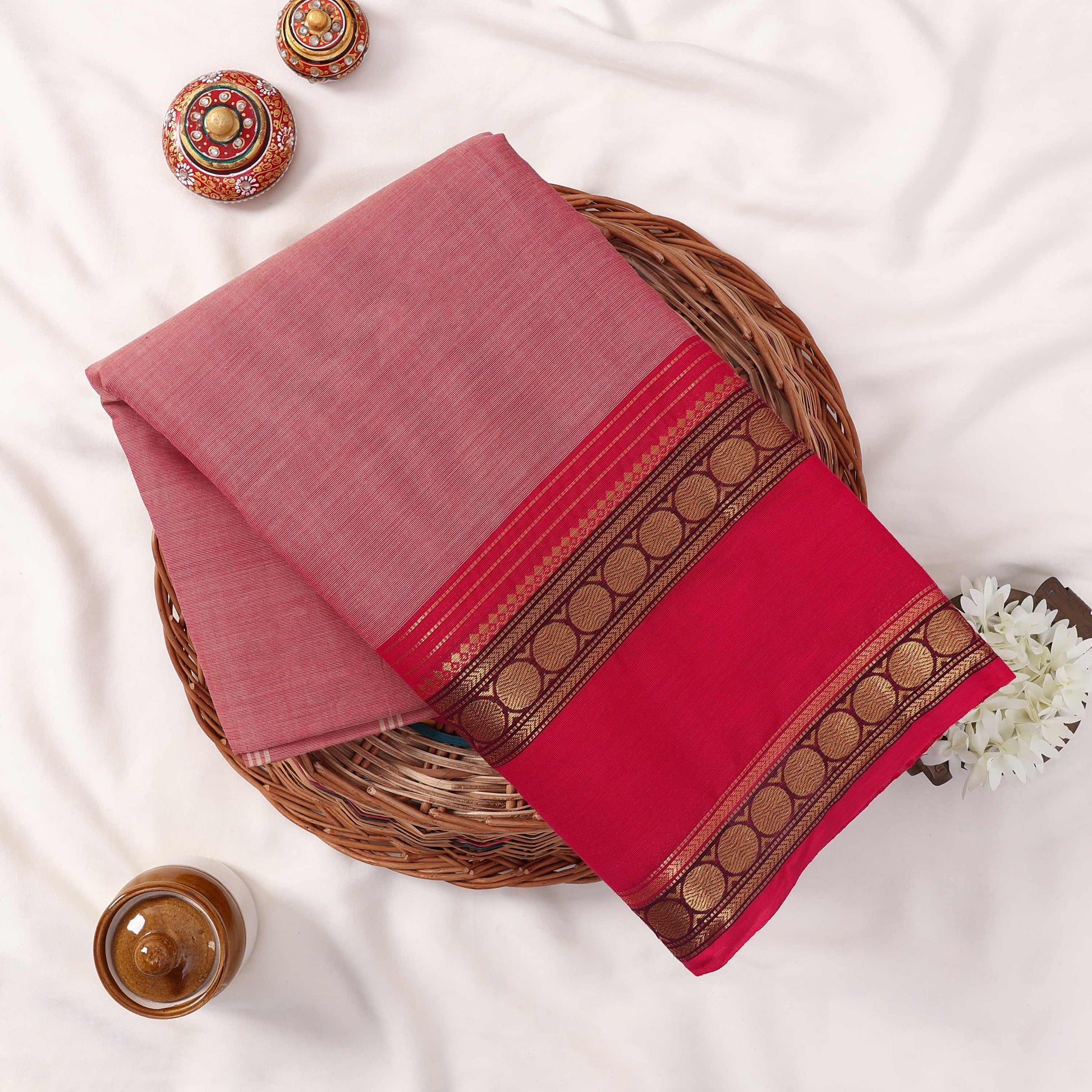 Kanchi Cotton Saree With Bright Pink And Pink Body Ornate Gold Woven Border Folded Display In Basket Top View
