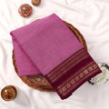 Kanchi Cotton Saree With Solid Pink Body And  Maroon Zari Border Folded Display On Wicker Basket Top View
