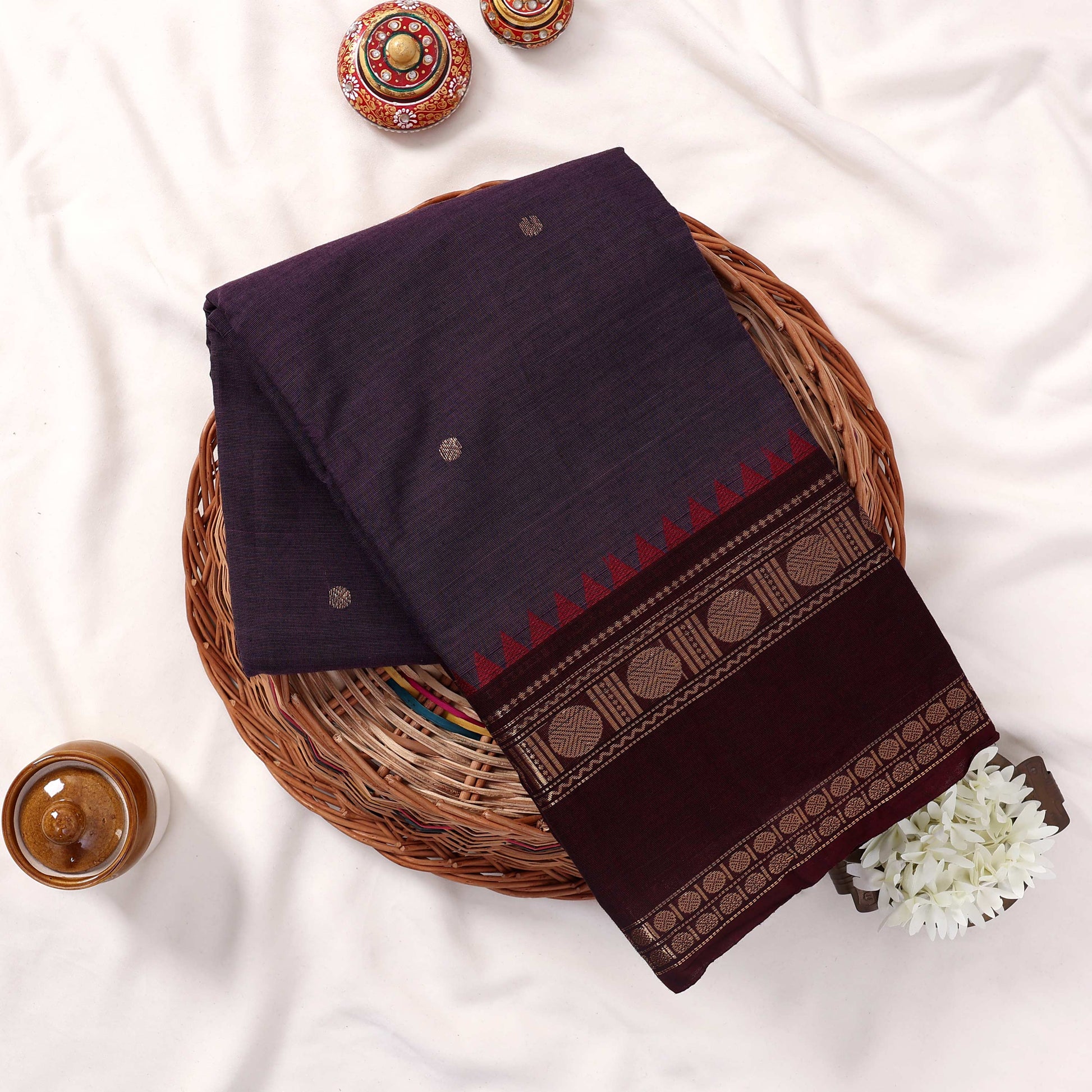 Kanchi Cotton Saree With Gold Zari Motifs And Maroon Border In Deep Purple Top View Folded Display In Basket
