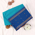 Chettinad cotton saree with teal body blue zari border and woven butta motifs folded flat front view.