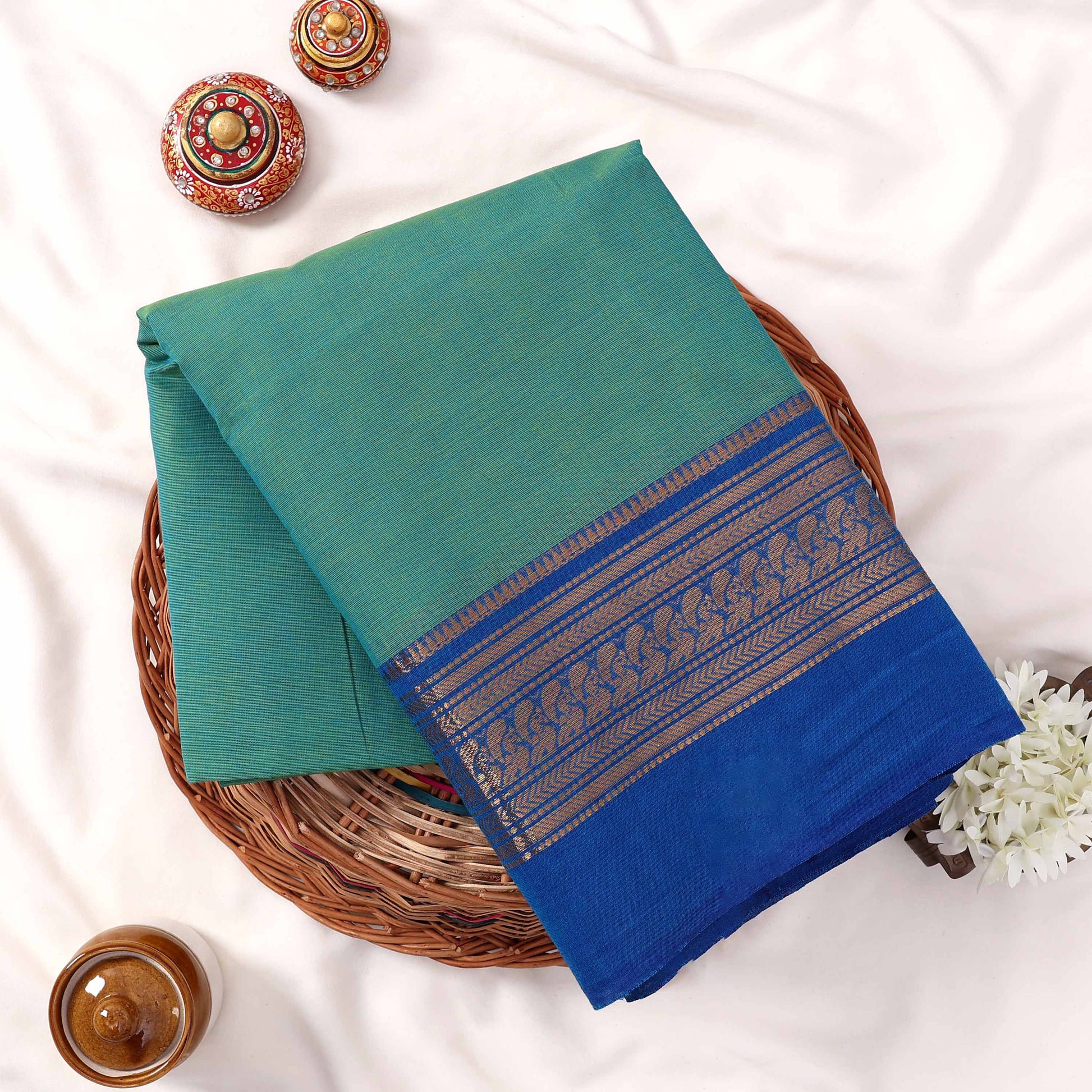 Kanchi Cotton Saree With Teal Green Body And Royal Blue Zari Border Top View Flat Lay With Decorative Accents 