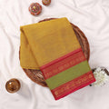 Kanchi Cotton Saree With Textured Yellow Body Green Panel And Red Zari Border Folded Flat Lay View With Decor Accents
