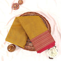 Kanchi Cotton Saree With Yellow Body And Pink Zari Woven Border Folded Flat Lay View With Decorative Basket And Floral Accents
