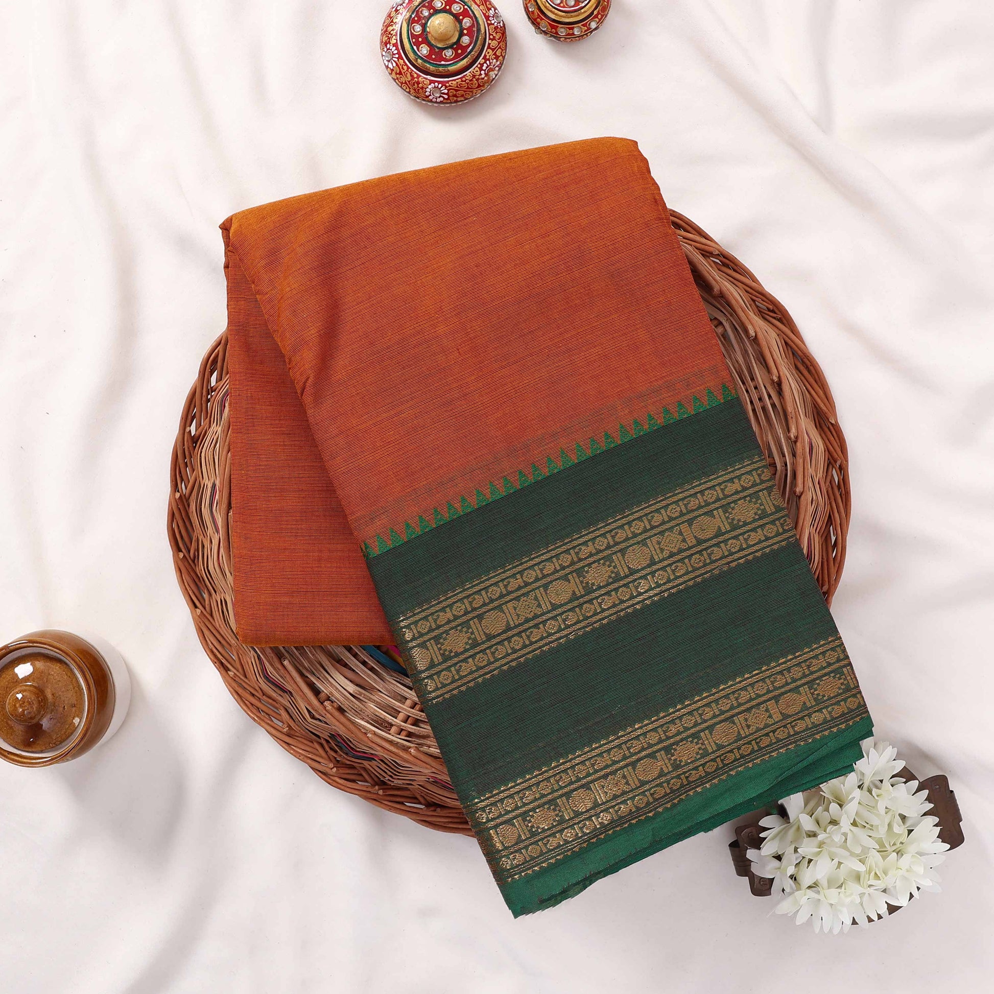 Kanchi Cotton Saree In Yellow With Dark Green Zari Border Folded Display Top View With Decorative Accents

