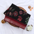 Black Semi Chanderi saree with floral leaf print and contrast zari woven border folded flat lay display.