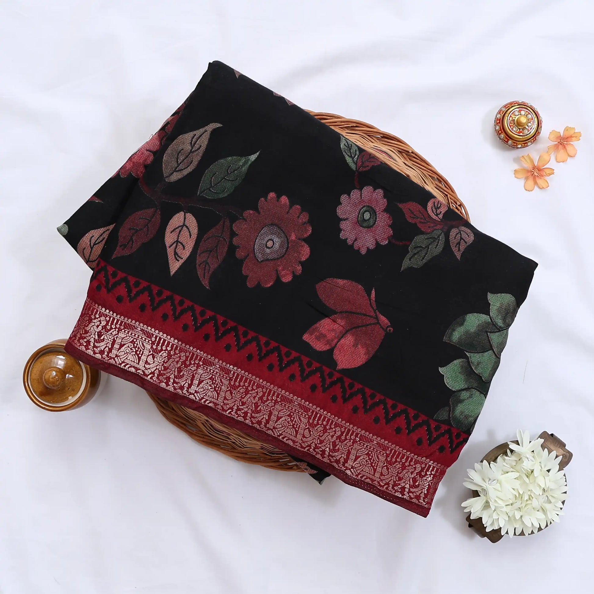 Black Semi Chanderi saree with floral leaf print and contrast zari woven border folded flat lay display.