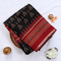 Semi Chanderi saree with black body red woven border and traditional motifs folded top view.