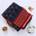 Semi Chanderi saree with navy blue body red woven border and traditional motifs folded top view.
