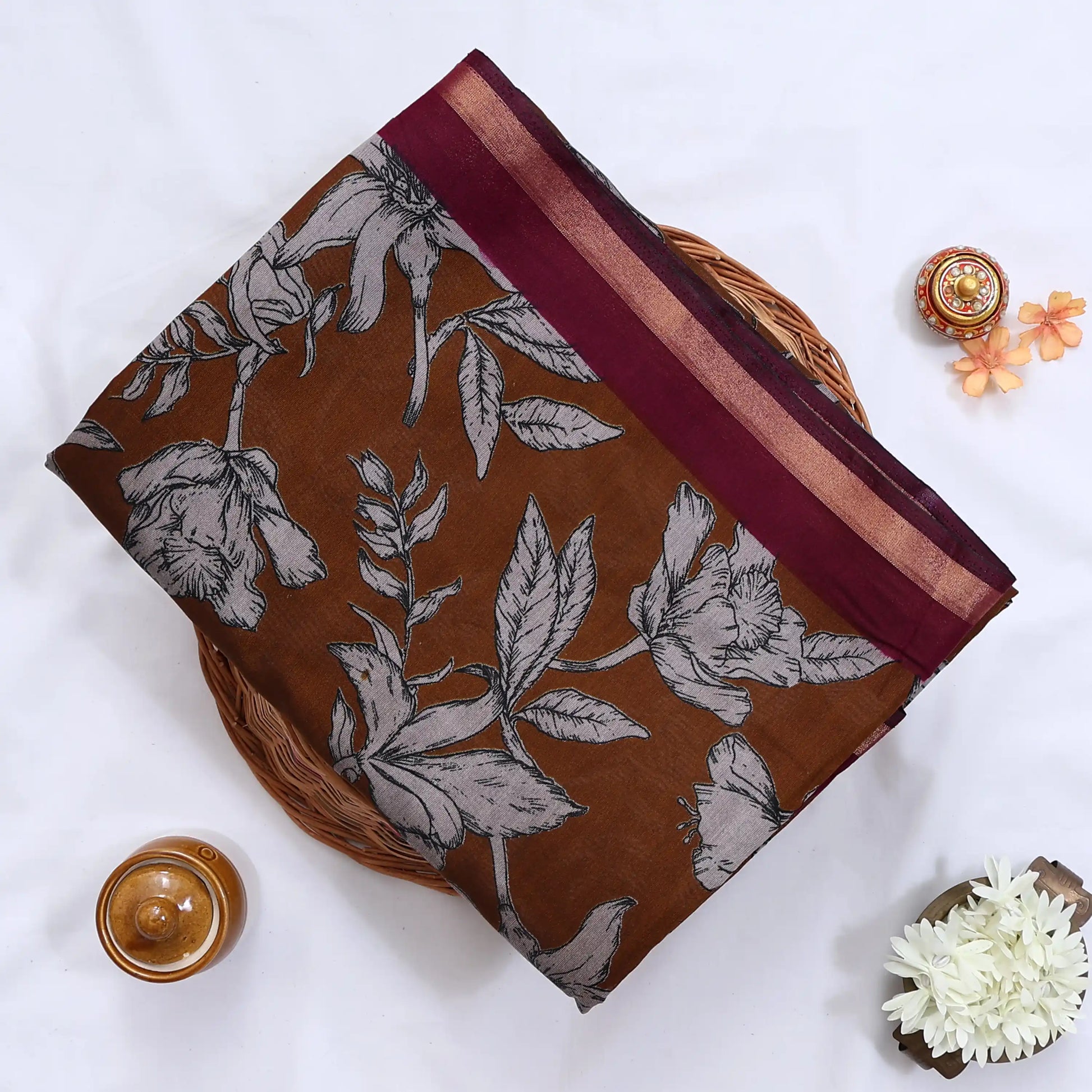 Brown semi Chanderi saree featuring white floral print and maroon border folded top view