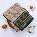 Cream Semi Chanderi saree with bandhani dot print and deer & floral woven border folded flat lay display.
