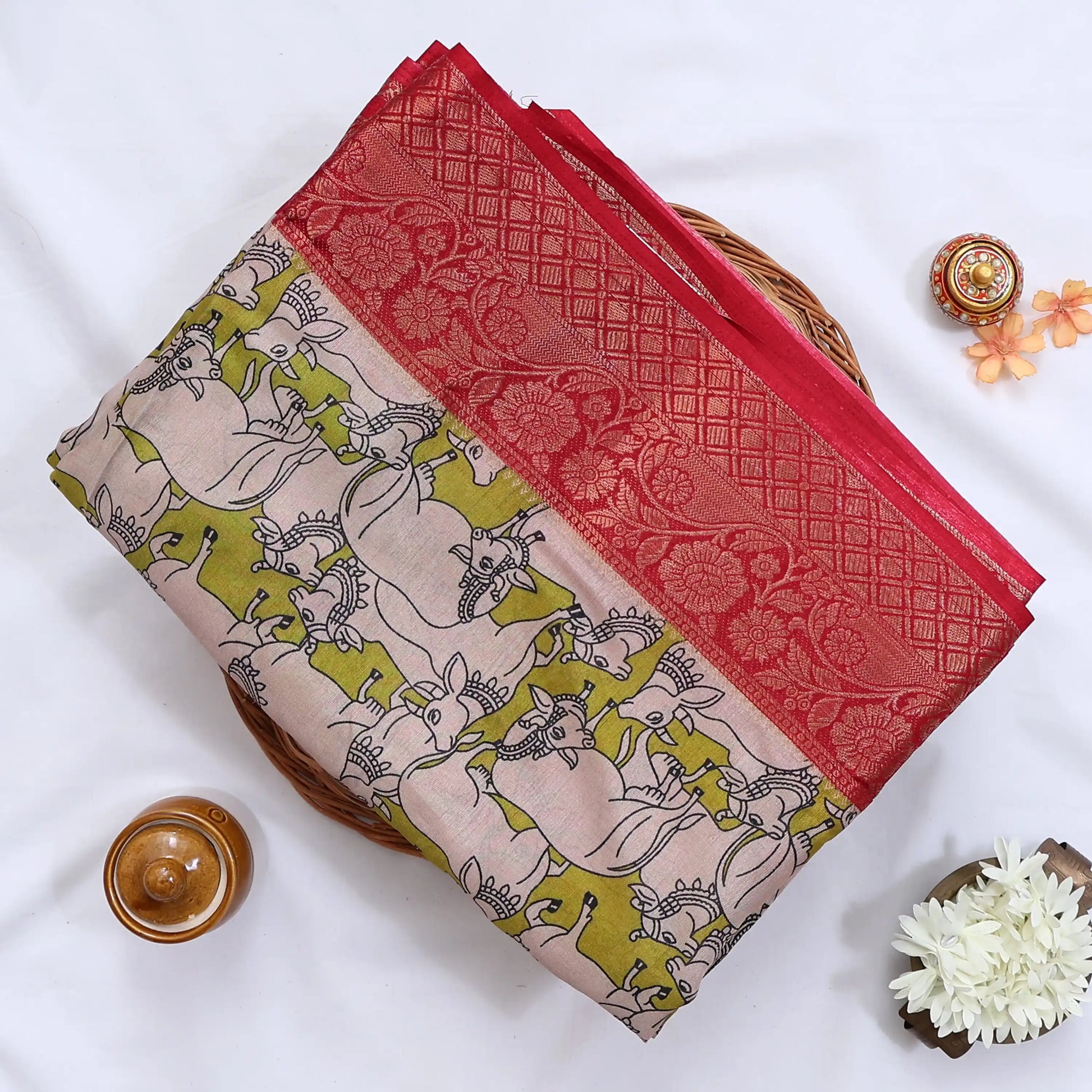 Semi Chanderi saree with cow motif print beige and olive green body with red zari border folded top view