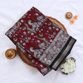 Maroon Semi Chanderi saree with floral peacock print and contrast woven border folded flat lay display.